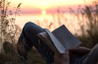 A person reading at sunrise with a focused, peaceful expression
